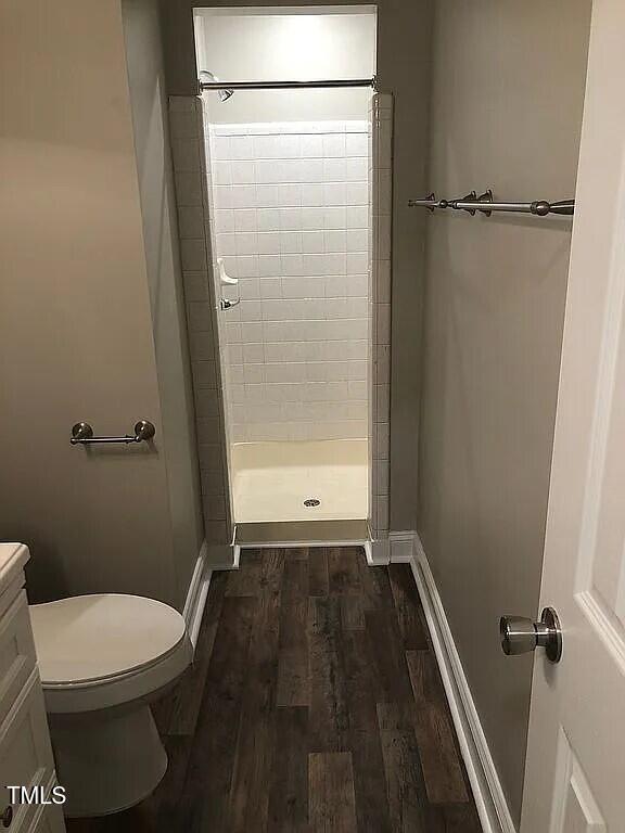 bathroom with wood-type flooring, vanity, toilet, and walk in shower