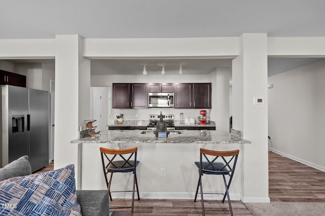 kitchen featuring a kitchen bar, appliances with stainless steel finishes, and light stone counters