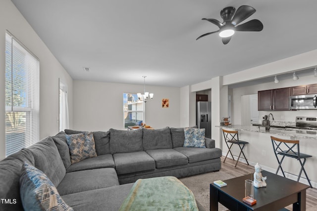 living room with rail lighting, sink, ceiling fan with notable chandelier, and light hardwood / wood-style floors