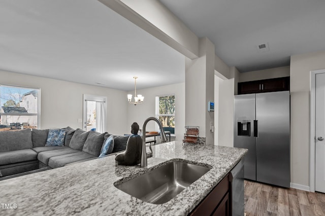 kitchen with light stone countertops, sink, dark brown cabinetry, and appliances with stainless steel finishes