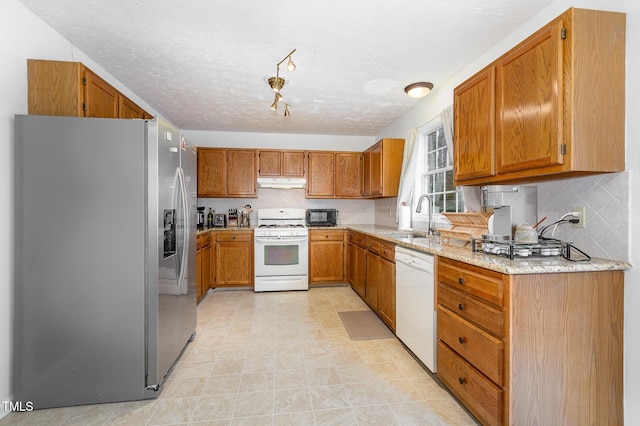 kitchen featuring a textured ceiling, light stone counters, sink, and white appliances