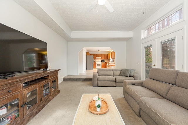 carpeted living room with ceiling fan, french doors, and a textured ceiling