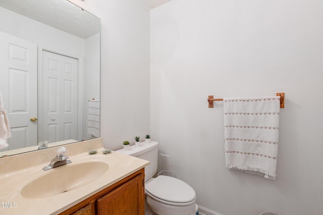 bathroom featuring a textured ceiling, vanity, and toilet