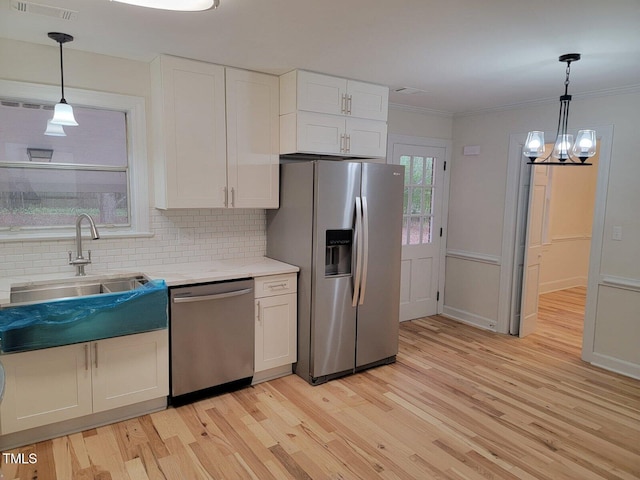 kitchen with hanging light fixtures, light hardwood / wood-style flooring, backsplash, white cabinets, and appliances with stainless steel finishes
