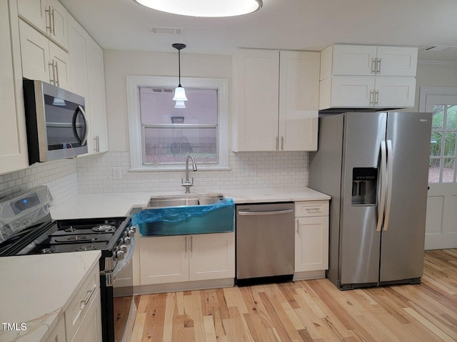 kitchen featuring pendant lighting, stainless steel appliances, white cabinetry, and sink