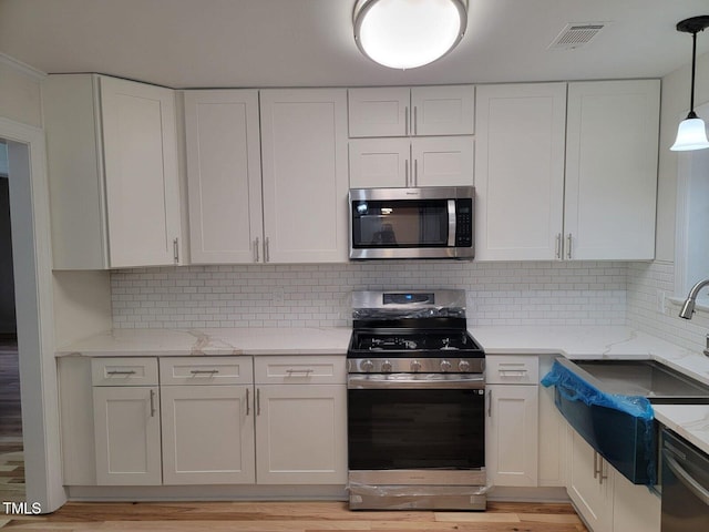 kitchen with decorative backsplash, white cabinets, and stainless steel appliances