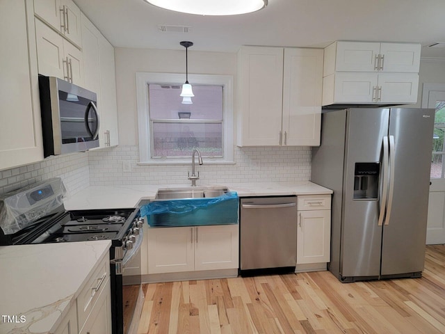 kitchen with backsplash, white cabinets, and appliances with stainless steel finishes