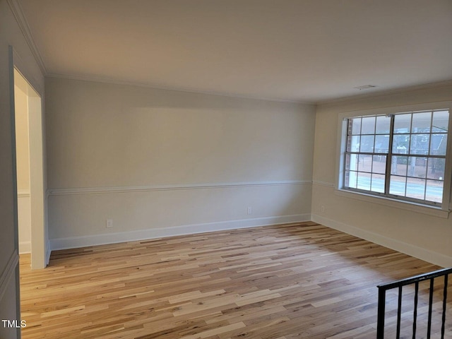 spare room with crown molding and light wood-type flooring