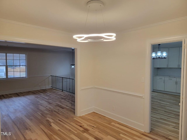 unfurnished dining area with a notable chandelier, crown molding, and light hardwood / wood-style flooring