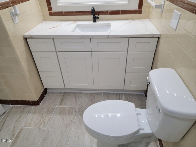 bathroom with vanity, tile walls, and toilet