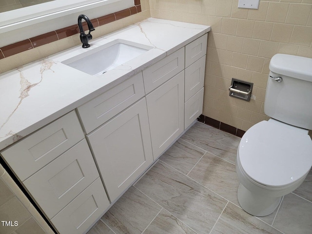bathroom with vanity, tile walls, and toilet