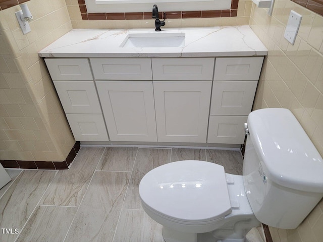 bathroom featuring vanity, toilet, and tile walls