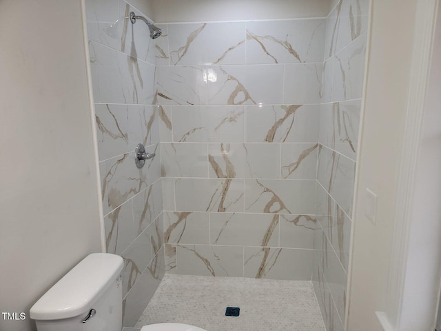 bathroom featuring toilet and a tile shower