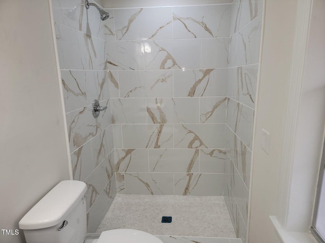 bathroom featuring tiled shower and toilet