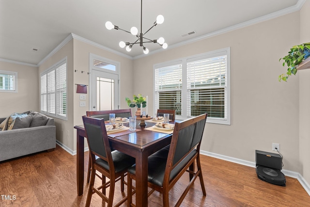 dining space with hardwood / wood-style floors, ornamental molding, and a chandelier