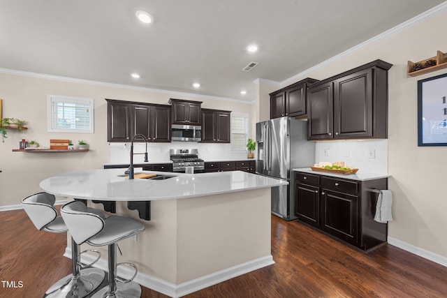 kitchen with stainless steel appliances, an island with sink, sink, and dark hardwood / wood-style flooring