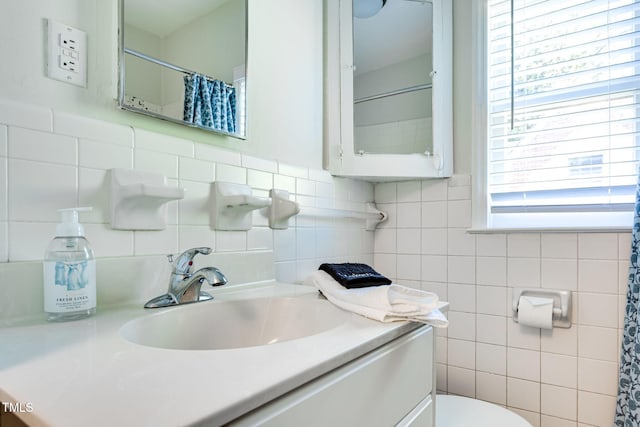 bathroom featuring vanity, toilet, and tile walls