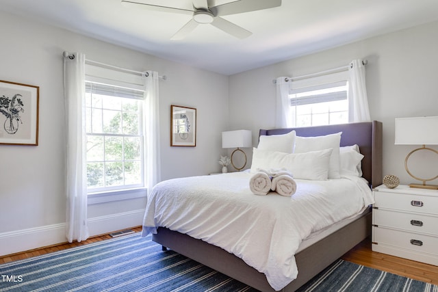 bedroom with ceiling fan, dark hardwood / wood-style flooring, and multiple windows