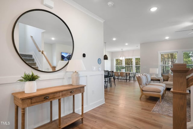 interior space with ceiling fan, ornamental molding, and light hardwood / wood-style flooring