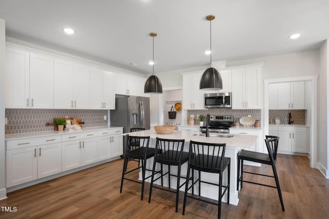 kitchen featuring decorative light fixtures, stainless steel appliances, white cabinetry, and sink