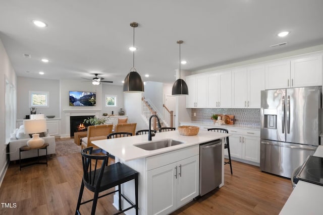 kitchen with hanging light fixtures, sink, an island with sink, appliances with stainless steel finishes, and white cabinetry