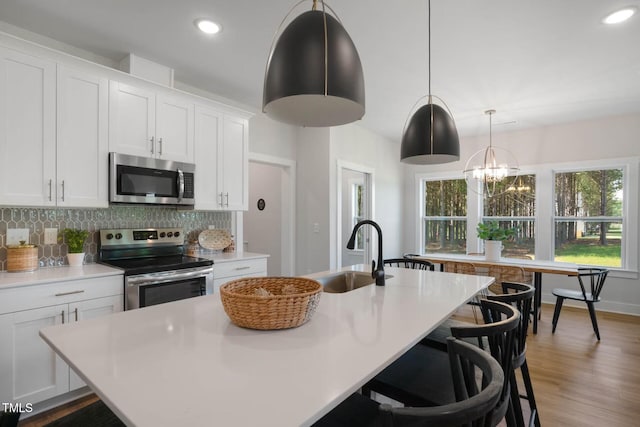 kitchen featuring a kitchen island with sink, sink, white cabinets, and stainless steel appliances