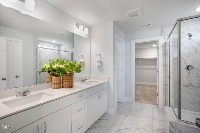 full bath featuring a sink, visible vents, marble finish floor, a marble finish shower, and a walk in closet