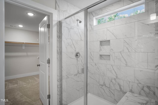 full bathroom with a spacious closet, a shower stall, visible vents, and baseboards