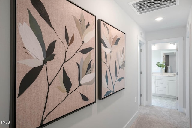 hall featuring visible vents, light carpet, and baseboards