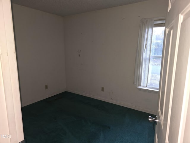 empty room featuring dark carpet and a textured ceiling