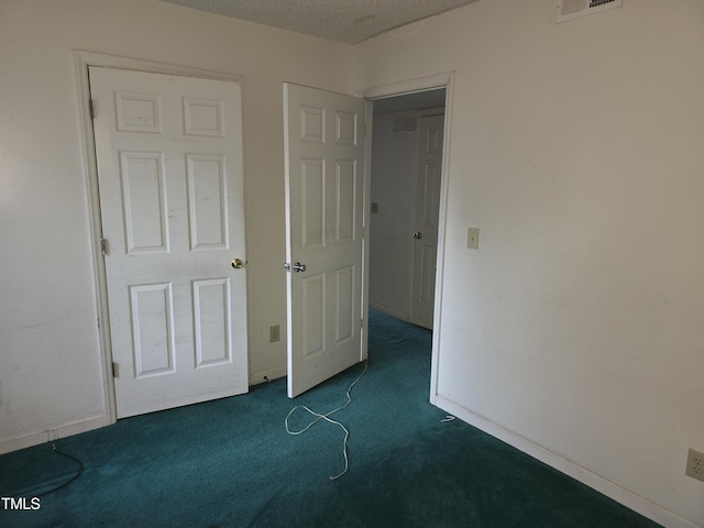 unfurnished bedroom with dark carpet and a textured ceiling