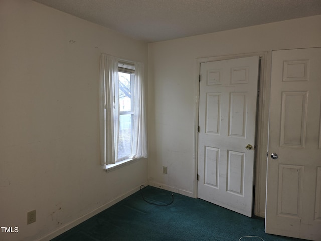 unfurnished bedroom featuring a textured ceiling and dark colored carpet