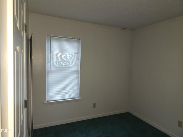 empty room with a textured ceiling and dark colored carpet