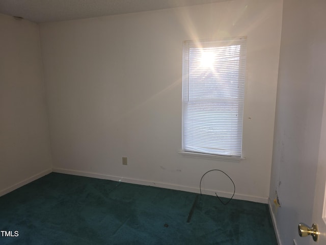 spare room featuring dark colored carpet and plenty of natural light