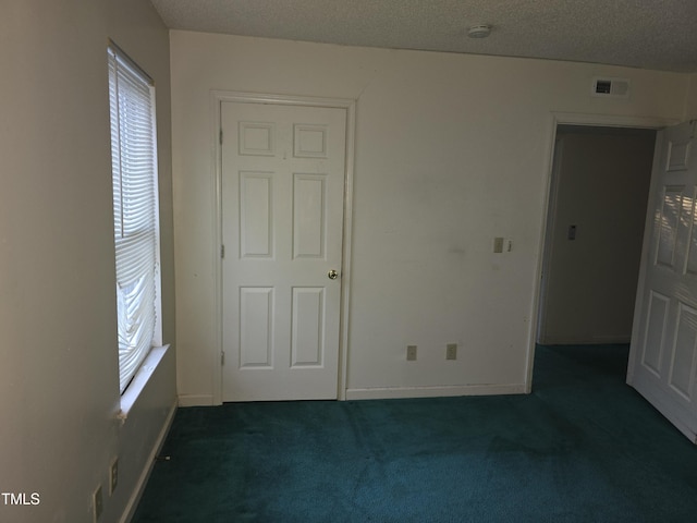 interior space with a textured ceiling and dark carpet