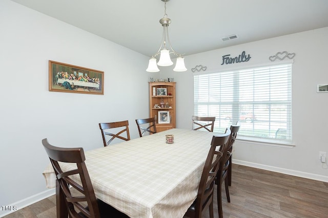 dining area featuring dark hardwood / wood-style flooring and an inviting chandelier