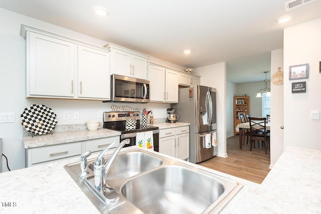 kitchen featuring light hardwood / wood-style floors, light stone countertops, sink, and appliances with stainless steel finishes