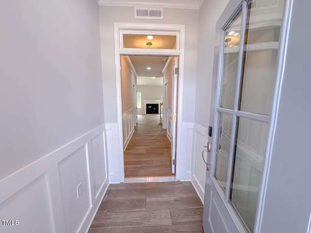 corridor with hardwood / wood-style flooring and crown molding