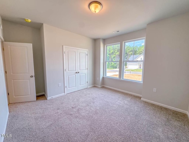 unfurnished bedroom featuring light carpet and a closet