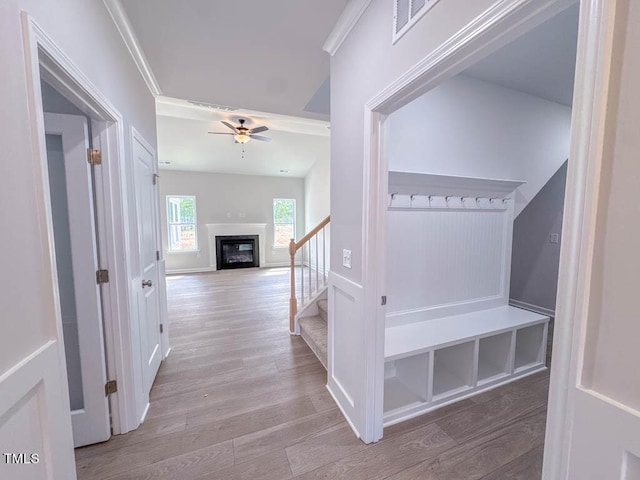 corridor featuring ornamental molding and light hardwood / wood-style flooring