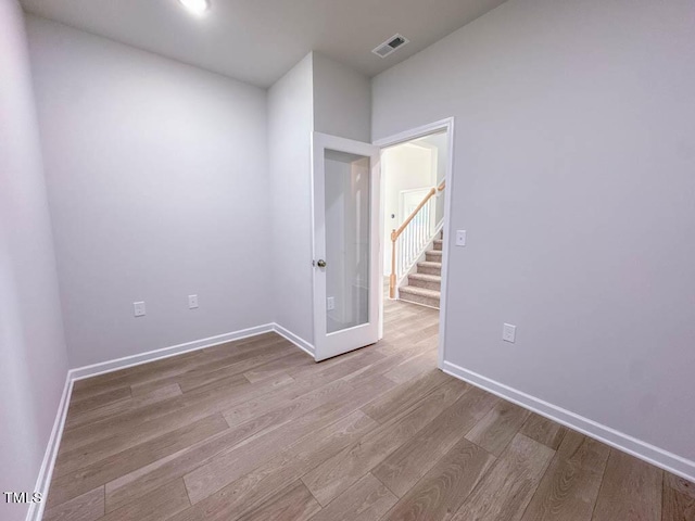 spare room with french doors and light hardwood / wood-style flooring