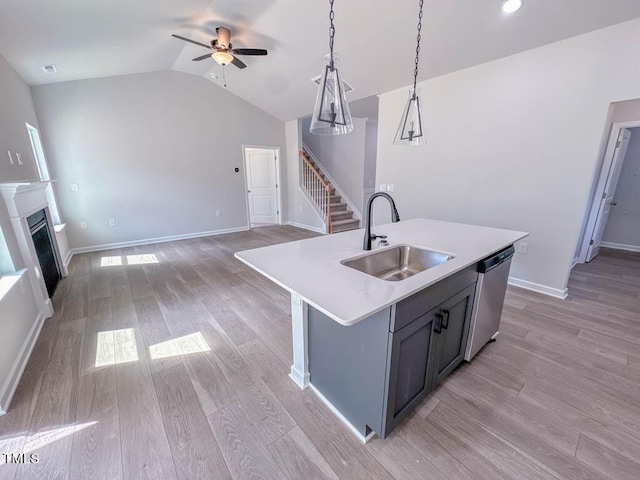 kitchen featuring sink, stainless steel dishwasher, pendant lighting, a center island with sink, and light wood-type flooring