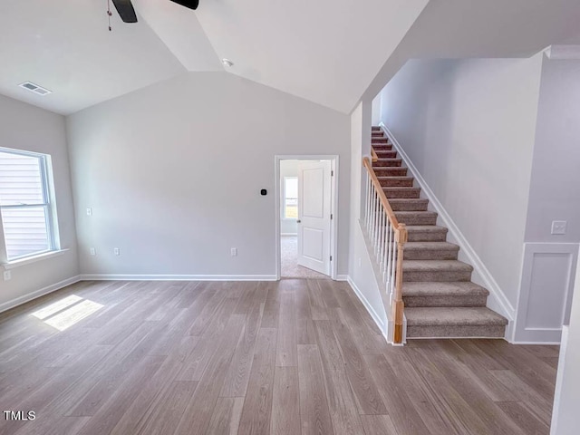 unfurnished living room featuring lofted ceiling, light wood-type flooring, ceiling fan, and a healthy amount of sunlight