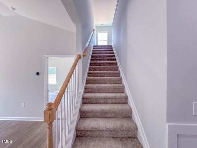 stairs featuring hardwood / wood-style floors, vaulted ceiling, and a wealth of natural light