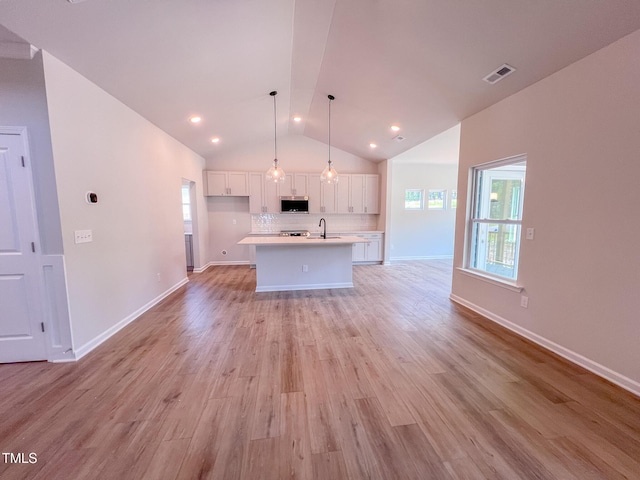 403 Duncan Creek Rd # 131, Lillington, NC 27546 - kitchen with stainless steel microwave, white cabinets, light countertops, open floor plan, and lofted ceiling