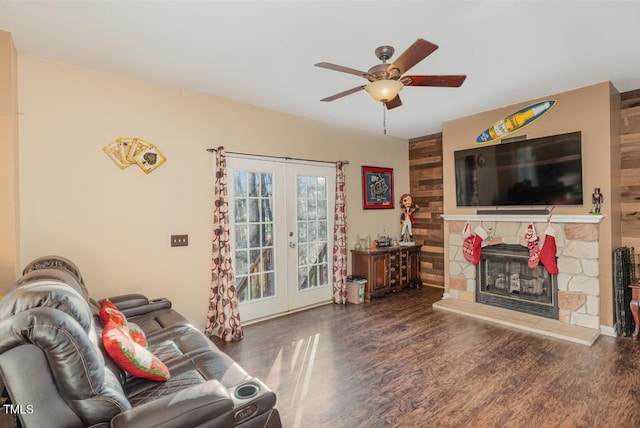 living room featuring french doors, dark hardwood / wood-style flooring, a stone fireplace, and ceiling fan