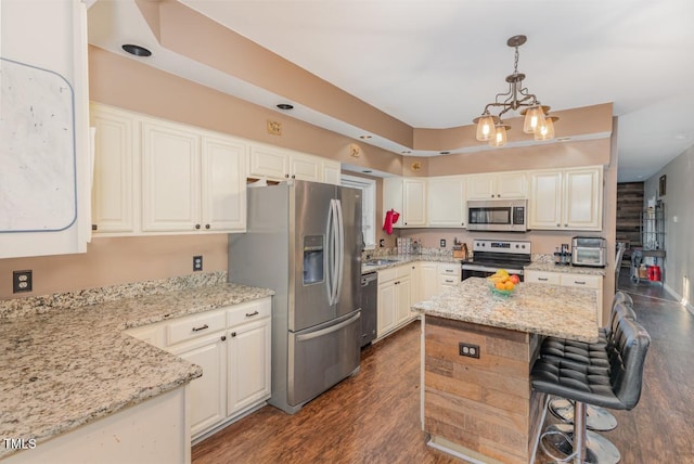 kitchen featuring pendant lighting, white cabinetry, light stone countertops, and stainless steel appliances