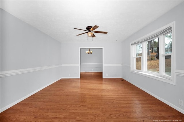unfurnished room with ceiling fan with notable chandelier and hardwood / wood-style flooring