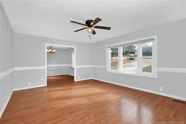 spare room featuring hardwood / wood-style floors and ceiling fan with notable chandelier
