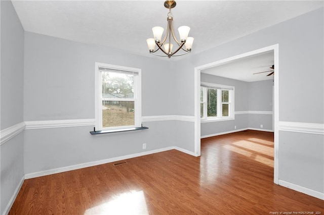 spare room with ceiling fan with notable chandelier and hardwood / wood-style flooring